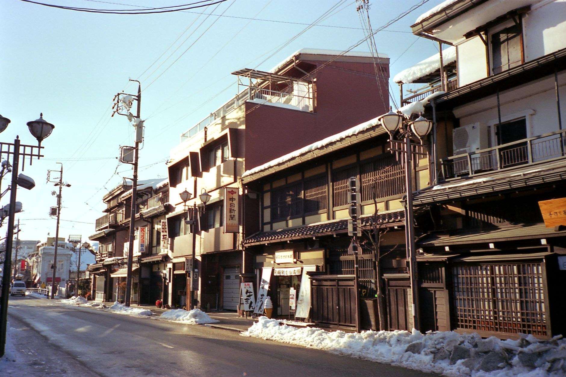 산마치 수지의 전통 목조 가옥 사이로 따뜻한 노을빛이 스며드는 골목길입니다.
