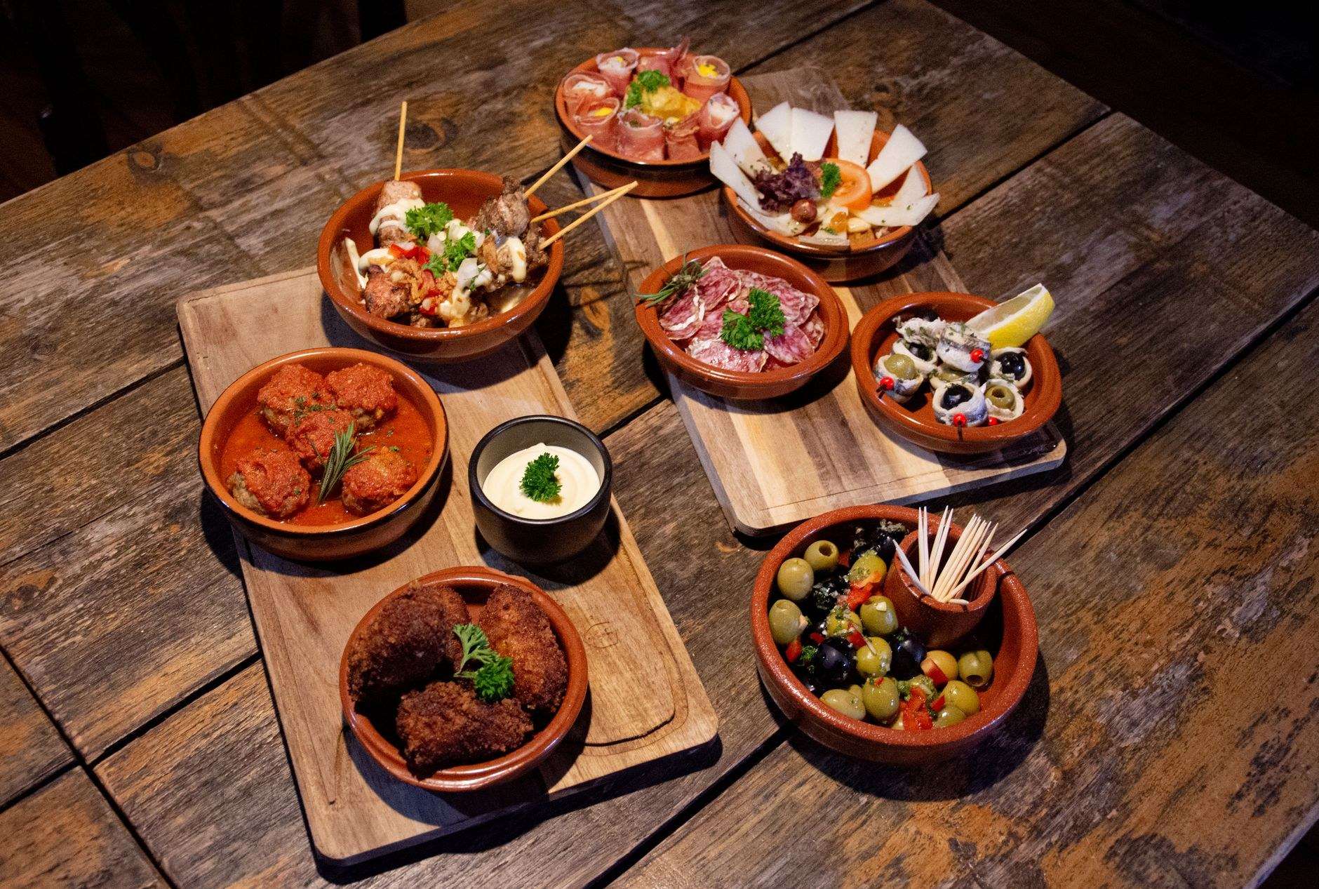 세비야의 한 타파스 바에서 맛볼 수 있는 신선한 하몽과 올리브, 현지 와인이 어우러진 식탁입니다.